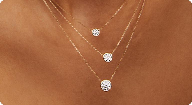 Image of model wearing multiple diamond pendants.