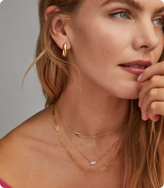 Image of model wearing earrings and multiple necklaces.